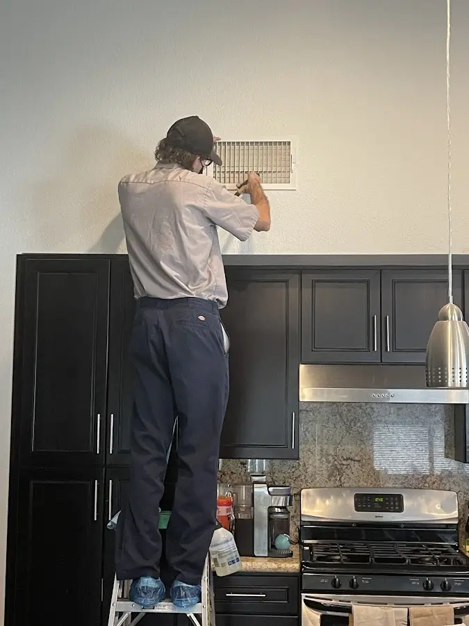 Technician inspecting an air vent during HVAC service in Scituate